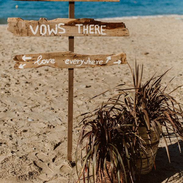 Beach wedding signage that says 'Shoes here, vows there, love everywhere'