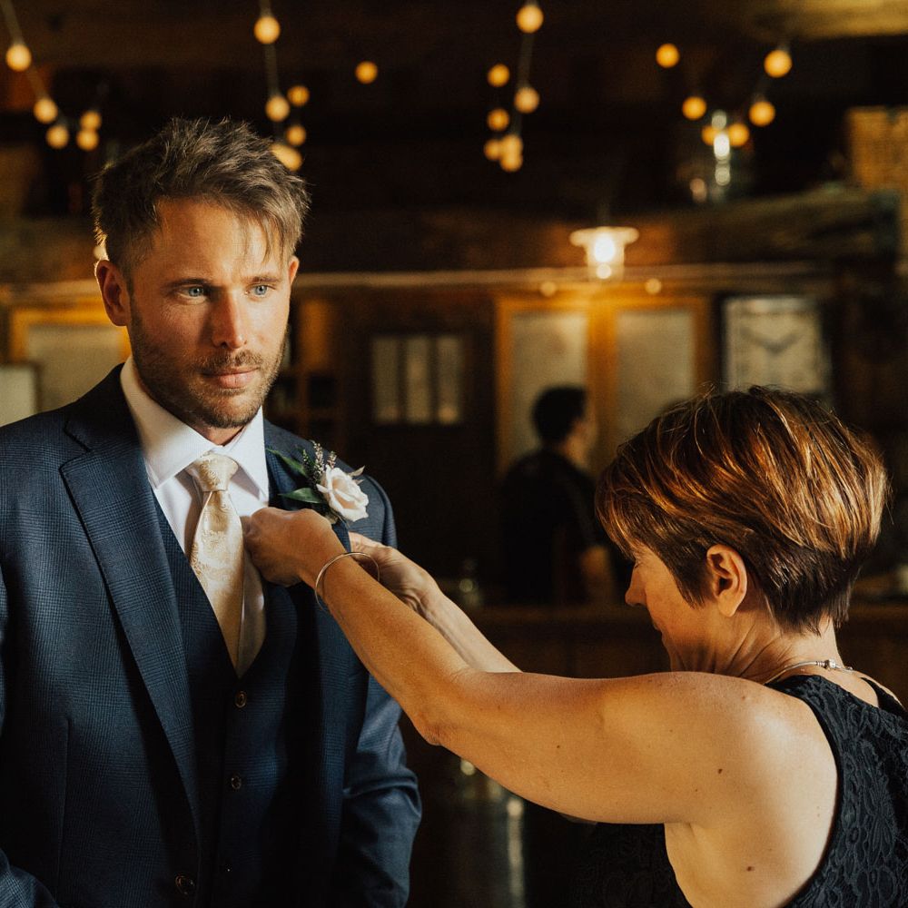 Groom in navy blue suit and gold tie with pink rose buttonhole