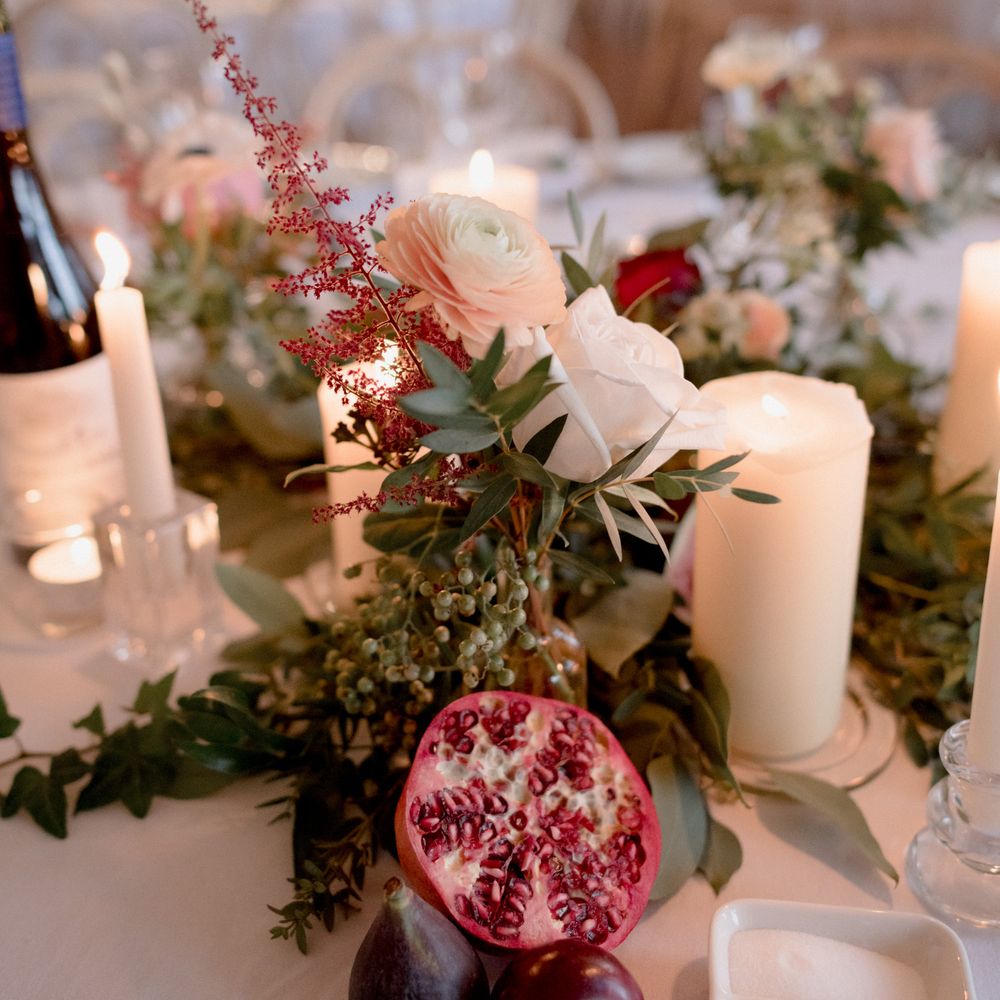 Wedding table décor with red flowers, plums and pomegranate 