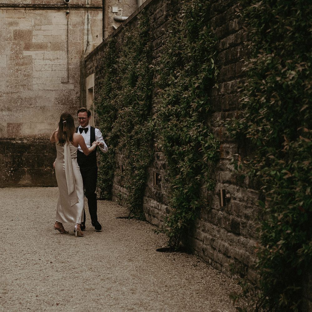 Brie & groom walk together whilst wearing reception outfits on the day of their wedding