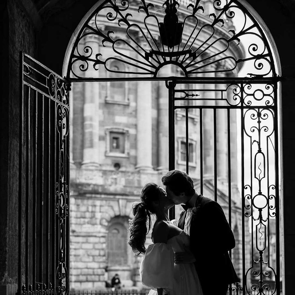 Black and white portrait of the stylish bride and groom kissing in the courtyard at Bodleian Library 