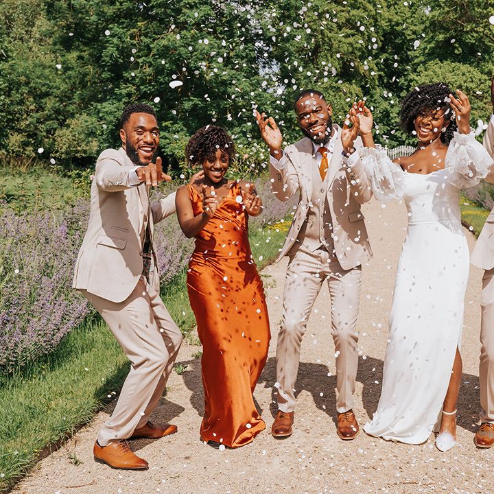 Wedding party confetti photograph with orange satin bridesmaid dresses, beige groomsmen suits and strapless wedding dress 