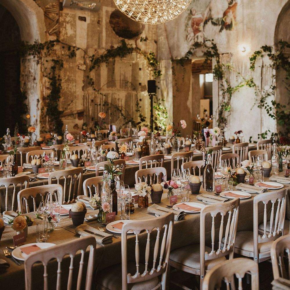 Ball lighting hangs from ceiling alongside vines climbing the walls and rustic tablescapes 
