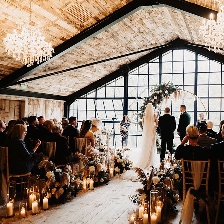 Bride and groom get married at black tie barn wedding venue in winter with chandeliers and moongate