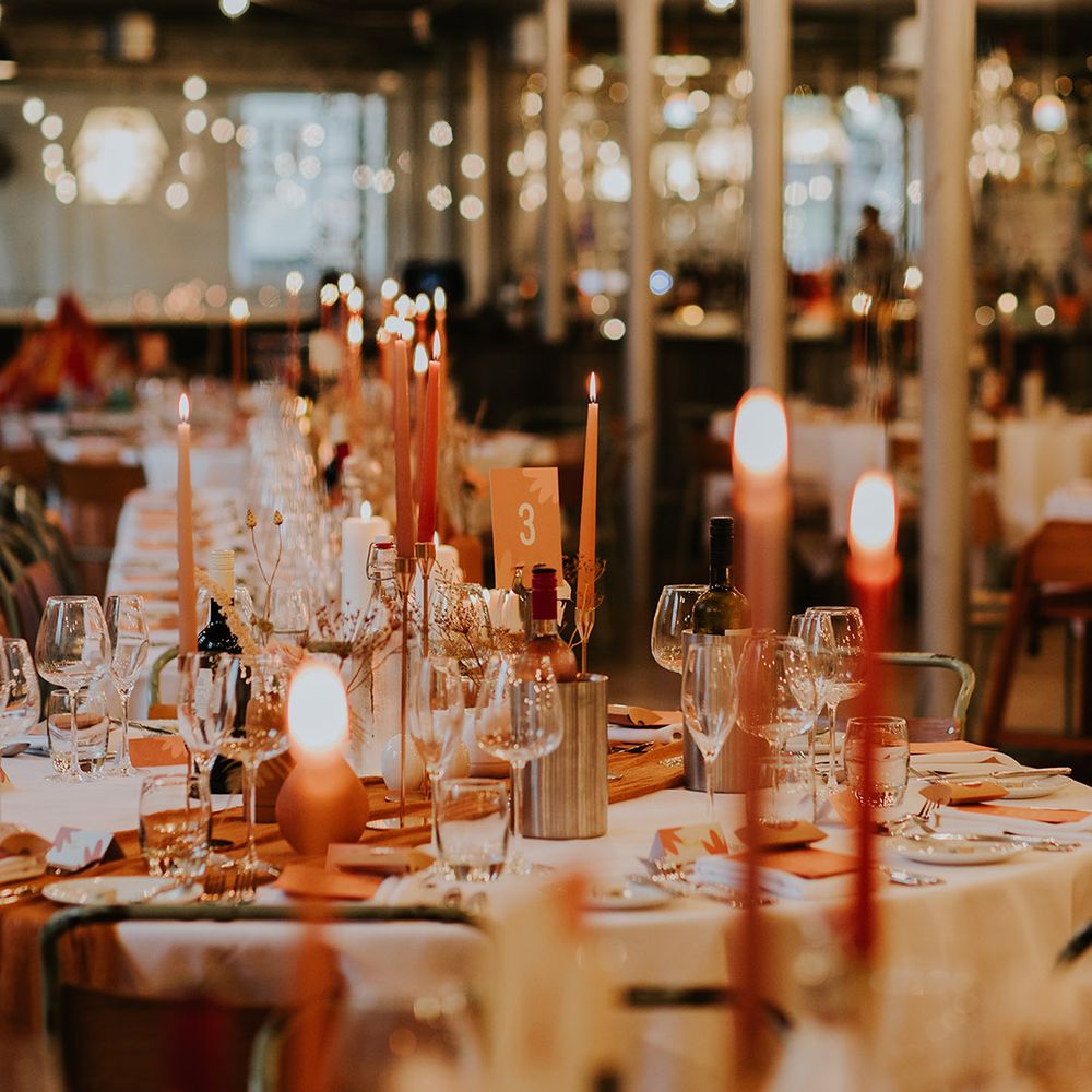 Orange table number sign with flower print and coloured candles and vases to match autumnal theme