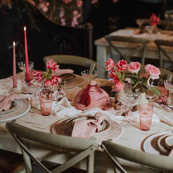 wedding table decor with wicker place mats, pink taper candles and pink floral arrangements 
