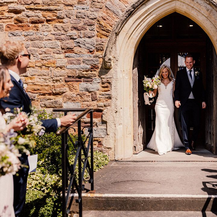 Bride and groom walk with intertwined hands out of their church wedding ceremony together 