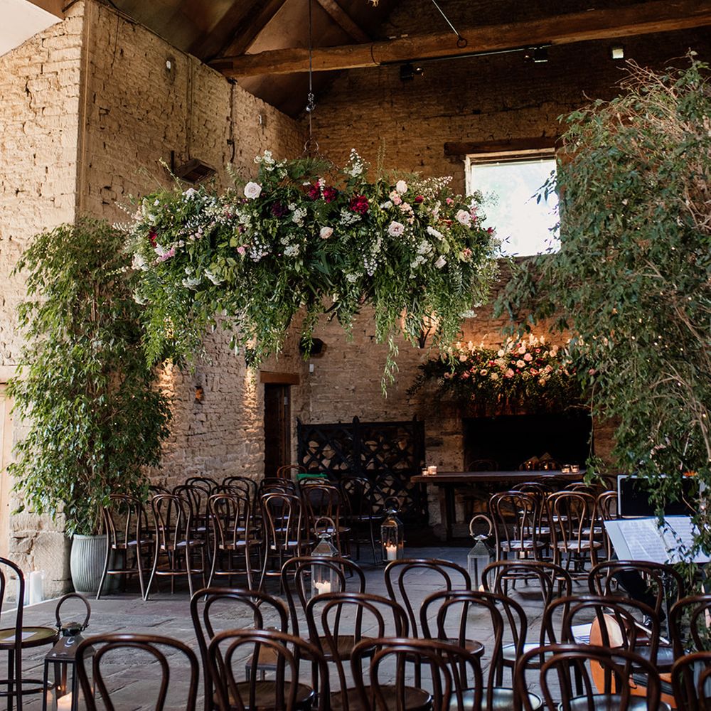 Cripps Barn wedding venue ceremony room with lots of greenery and colourful roses 