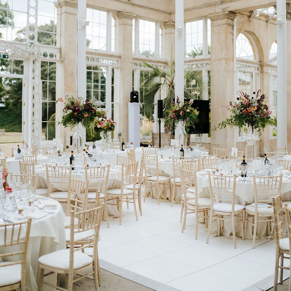 The Great Conservatory reception at Syon park, complete with clean tablescape styling and large bright floral centrepieces 