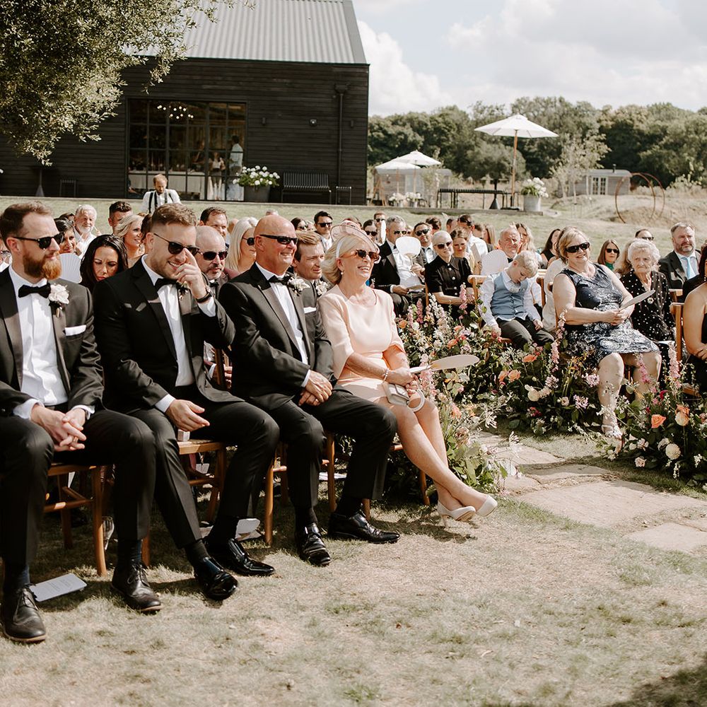 Wedding guests in black tie watch ceremony outdoors at Botley Hill Barn 