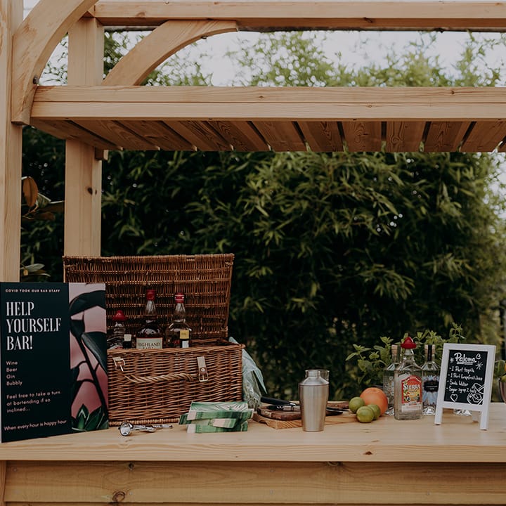 Help Yourself Bar with a basket of alcohol, citrus fruits, fresh water and a beer barrel
