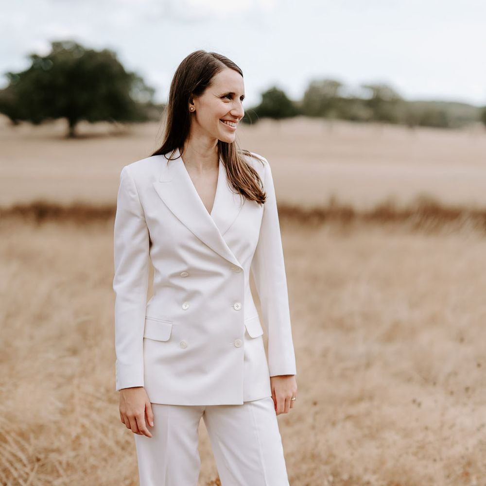 Bride in a double breasted white suit jacket and white suit trousers for the wedding 