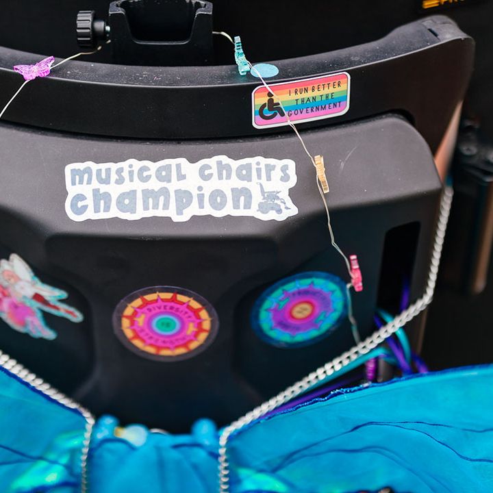 Bride's wheelchair with blue sparkly fairy wings attached and multiple colourful stickers 