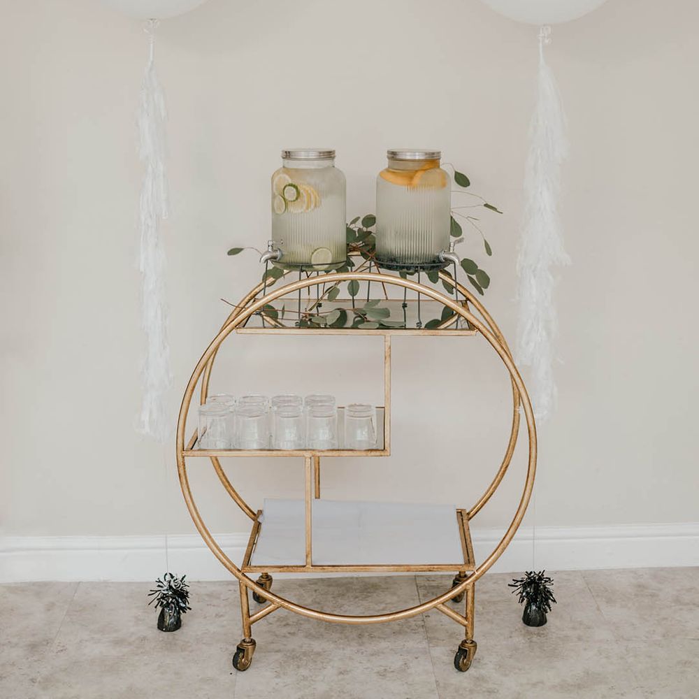 White wedding balloons with tassels with gold circle bar cart with fruit infused water drinks station 
