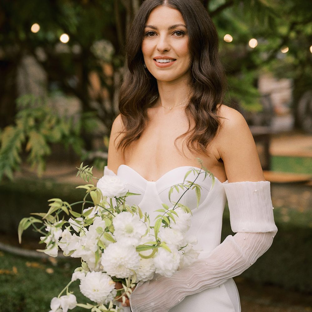 Corset style wedding dress from Bon Bride with detachable sleeves covered in pearls with white wedding flower bouquet 