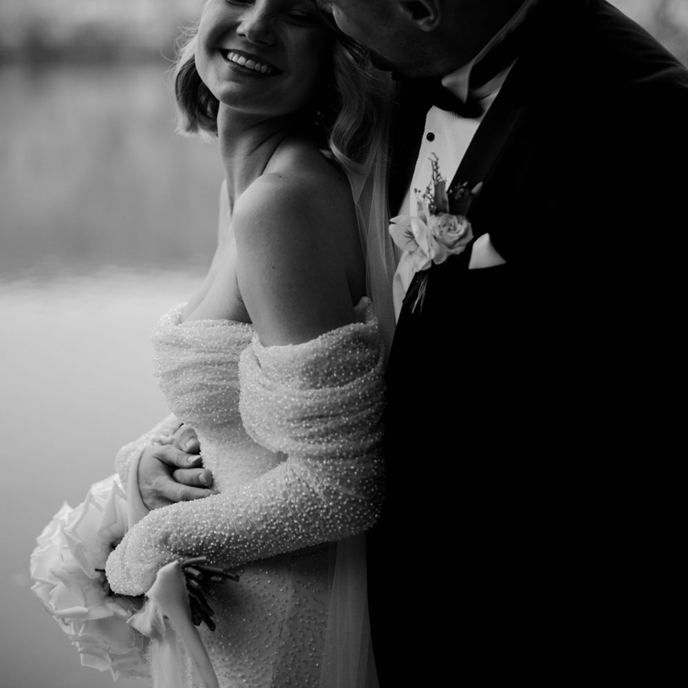 Groom in black tie embraces the bride from behind as they pose for their couple portraits at Wyresdale Park 