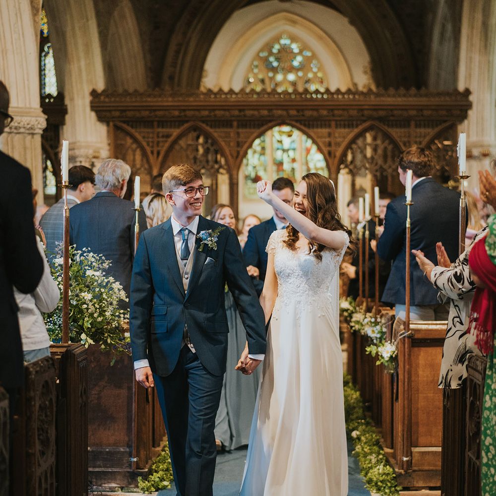 Bride and groom celebrate and smile brightly as they walk back down the aisle as a married couple