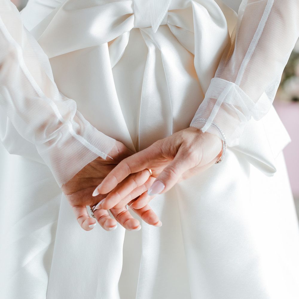 French tip wedding nails worn by bride in long sleeve mesh wedding dress 