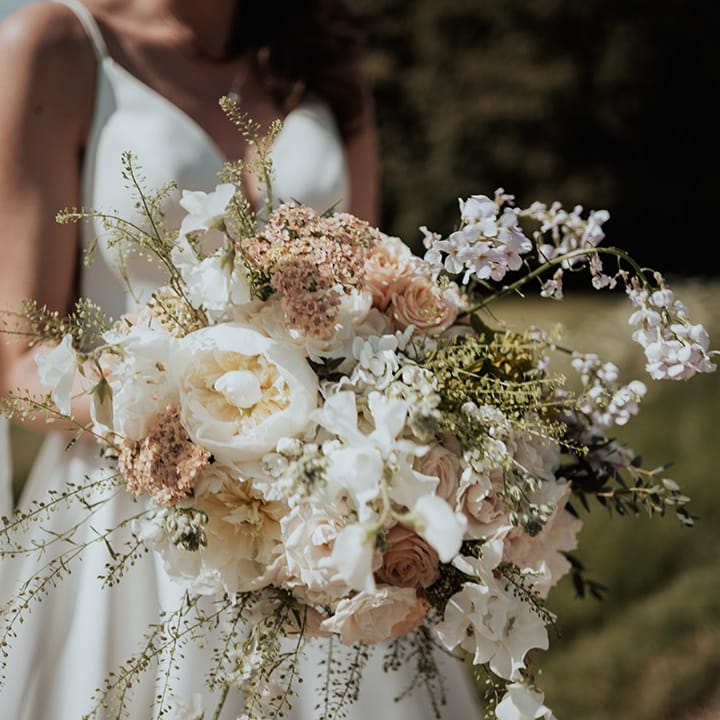 Bride holding a classic white and pale pink wedding bouquet with roses