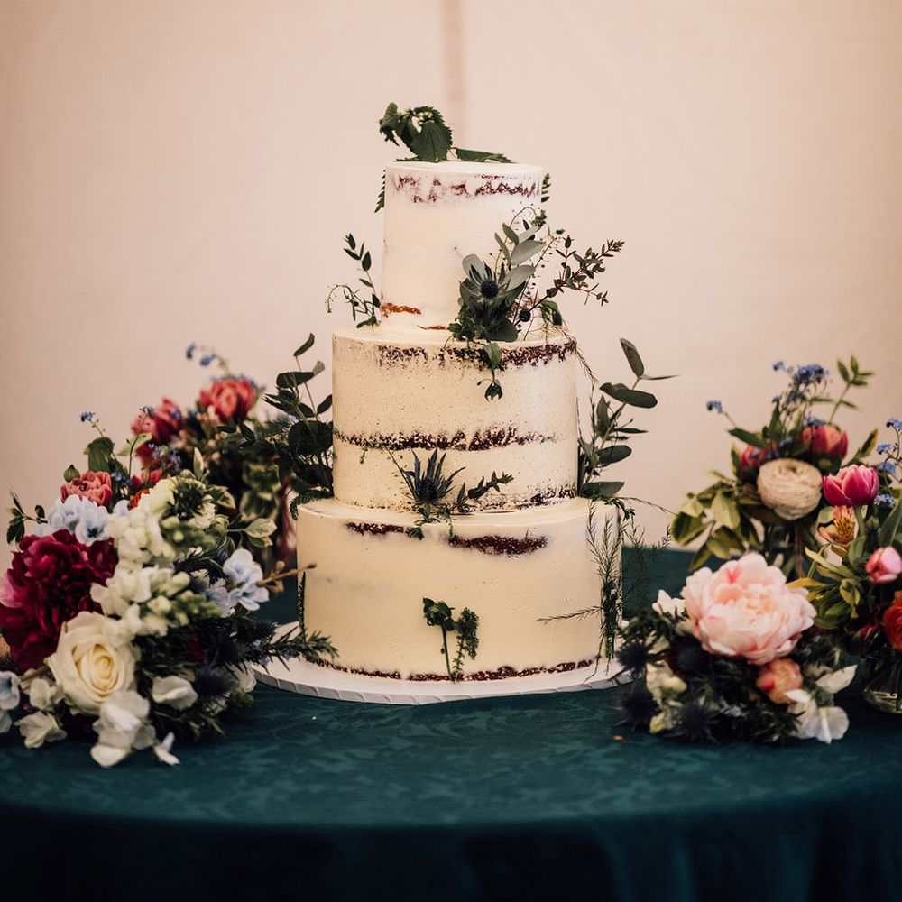 Three tier semi naked rustic wedding cake decorated with white frosting 