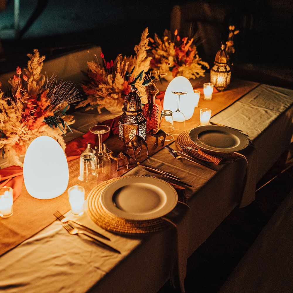 Romantic wedding tablescape with warm lighting and mini metal camels for boho destination wedding 
