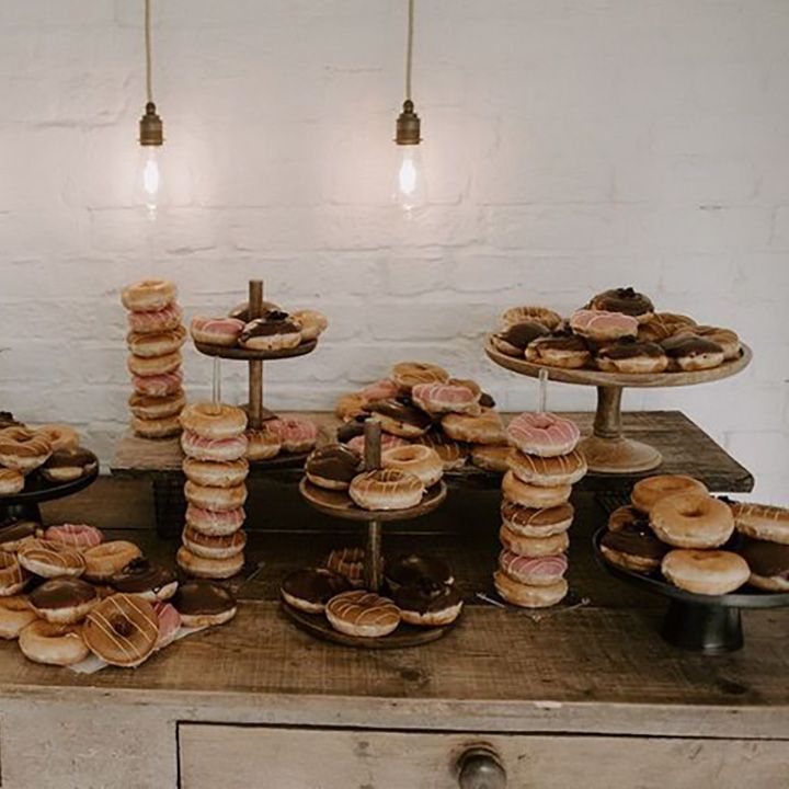 Dreamy dessert table with towers and plates of doughnuts in different flavours with coloured icing 