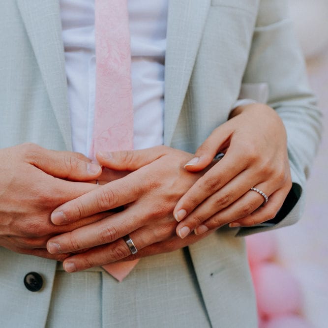 Bride and groom embracing and showing off wedding jewellery 