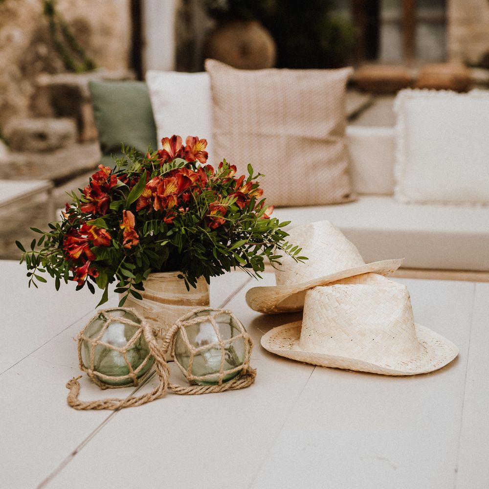 Two white wicker hats next to colourful floral bouquet on table