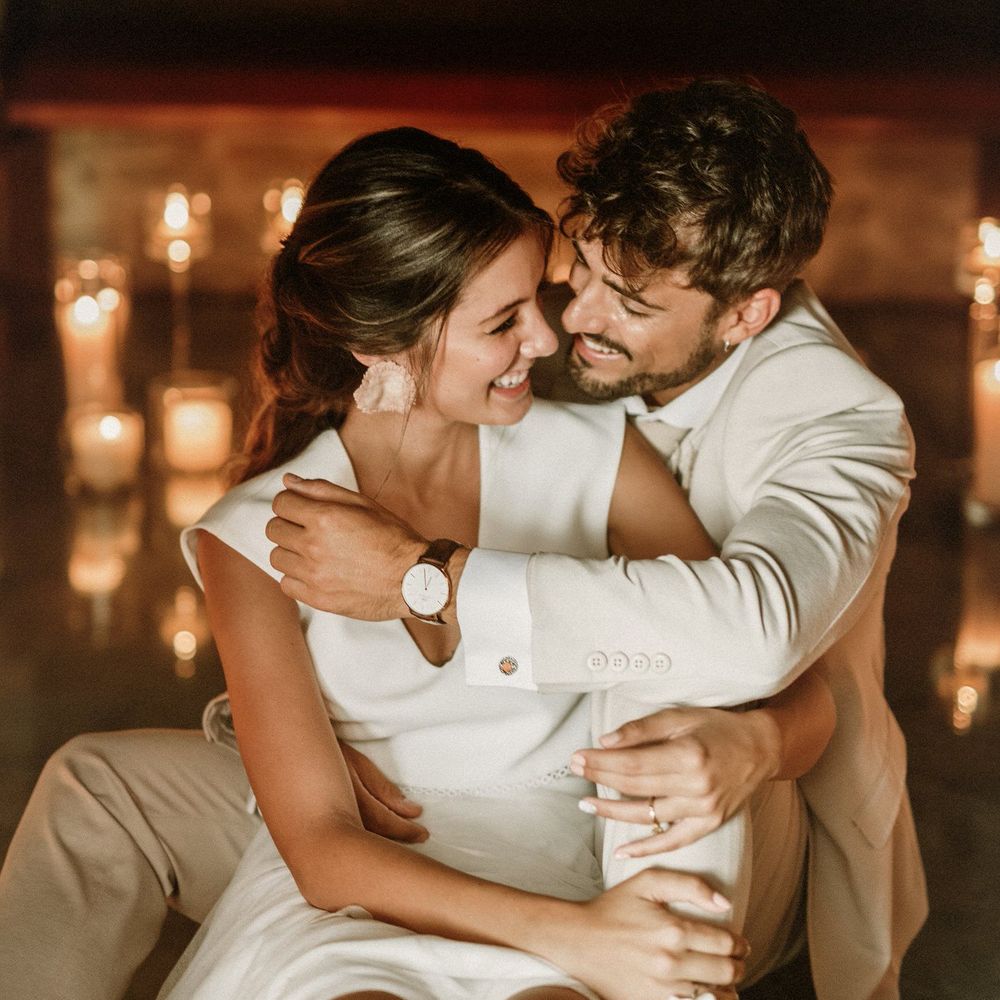 Groom in a beige suit embracing his boho bride in separates 