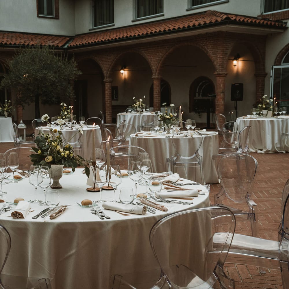 Elegant wedding reception with ghost chairs, blue and green floral centrepieces and candles 