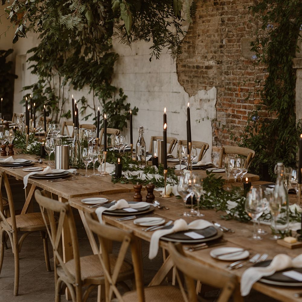 Wooden wedding table with rustic decor, wooden chairs, foliage cloud, greenery and black candles in the Fig House at Middleton Lodge