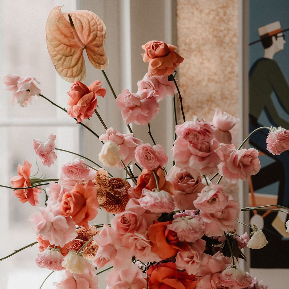 Pink and peach wedding flower display with  ranunculi, garden roses and orchids