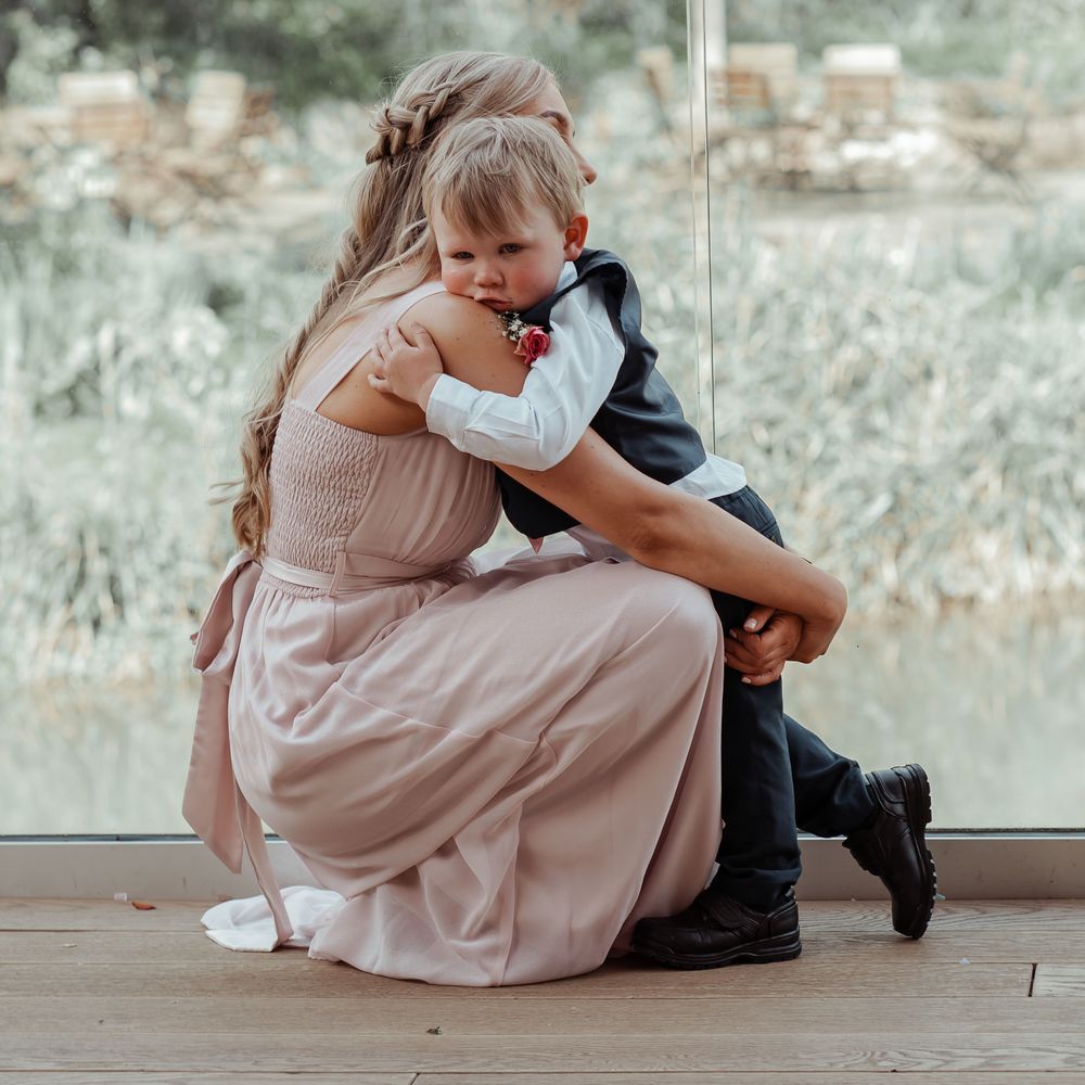 Little boy hugs bridesmaid 