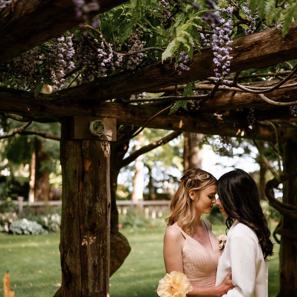 Two brides embracing at the end of their al fresco wedding reception 