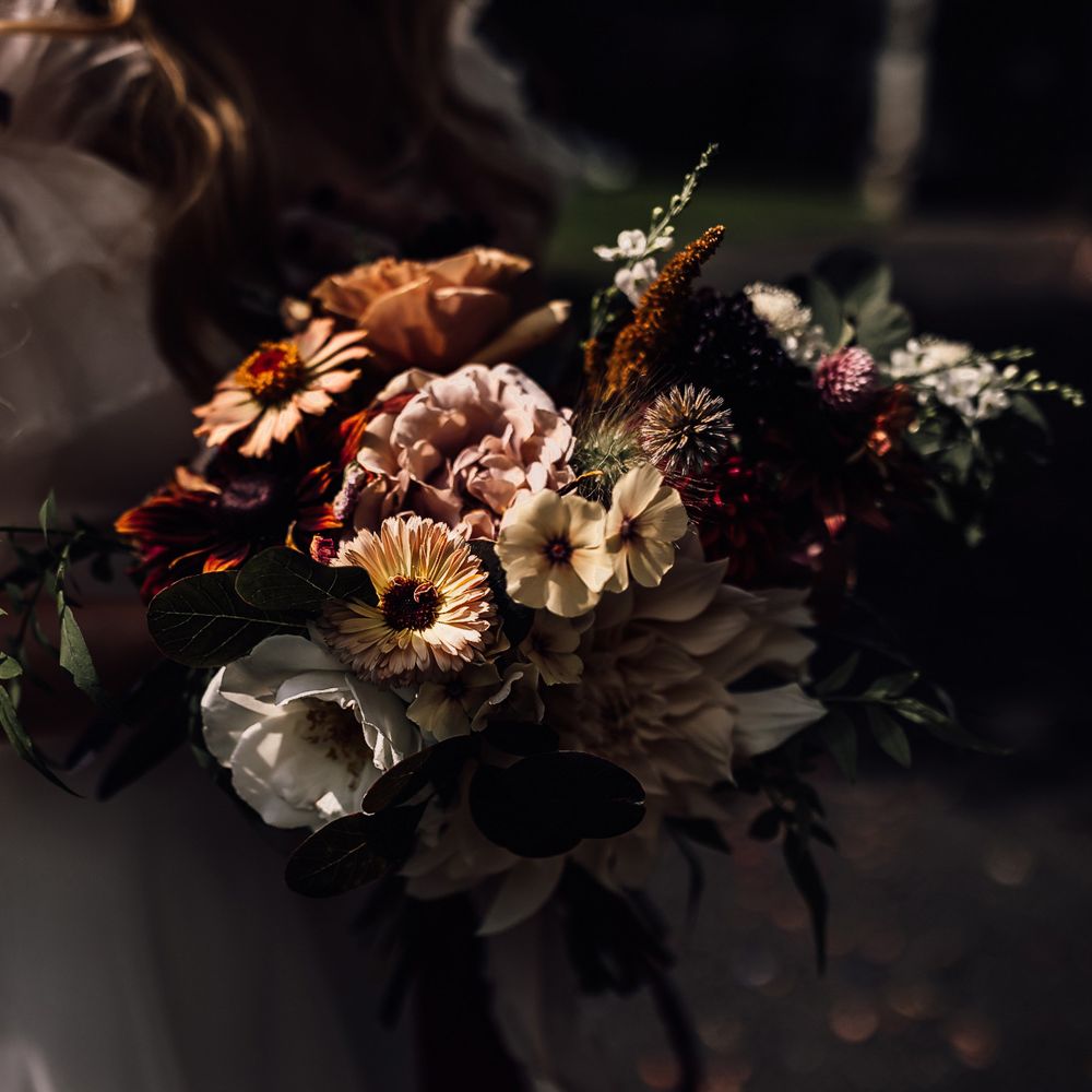 Bride in Halfpenny London Mayfair dress holding mixed bridal bouquet with yellow, pink and red flowers at wedding in Cornwall