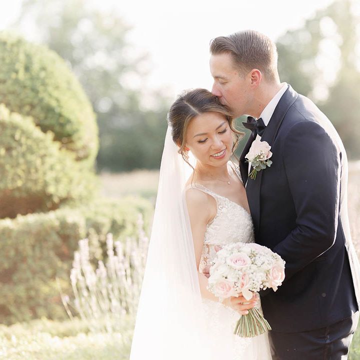 Groom kisses his bride outdoors on the day of their wedding