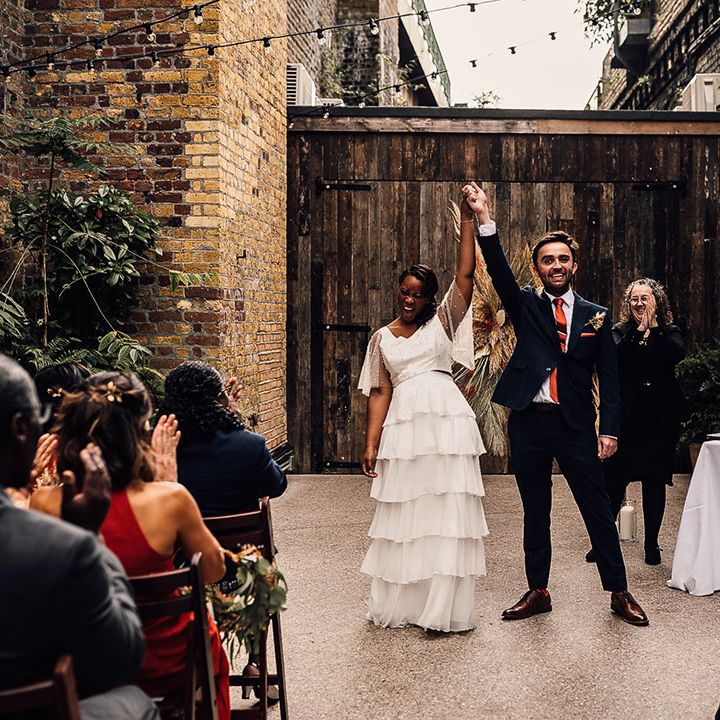 Civil wedding ceremony at 100 Barrington with bride in a layered skirt and pearl top holding hands with her groom in a navy suit at the altar 