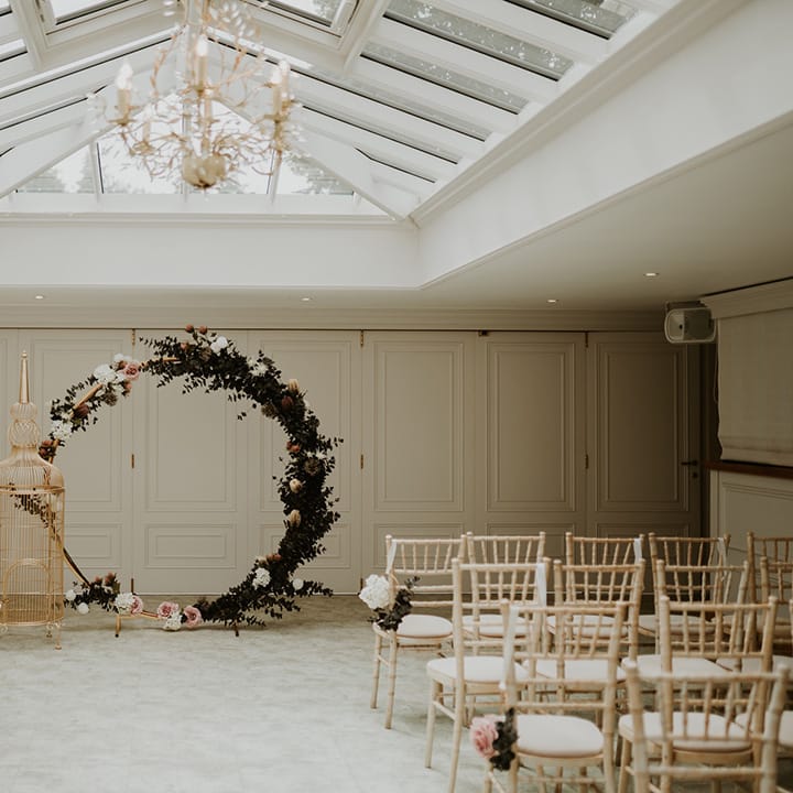 Floral circular archway complete with pink roses and large gilded golden birdcage to the front of aisle