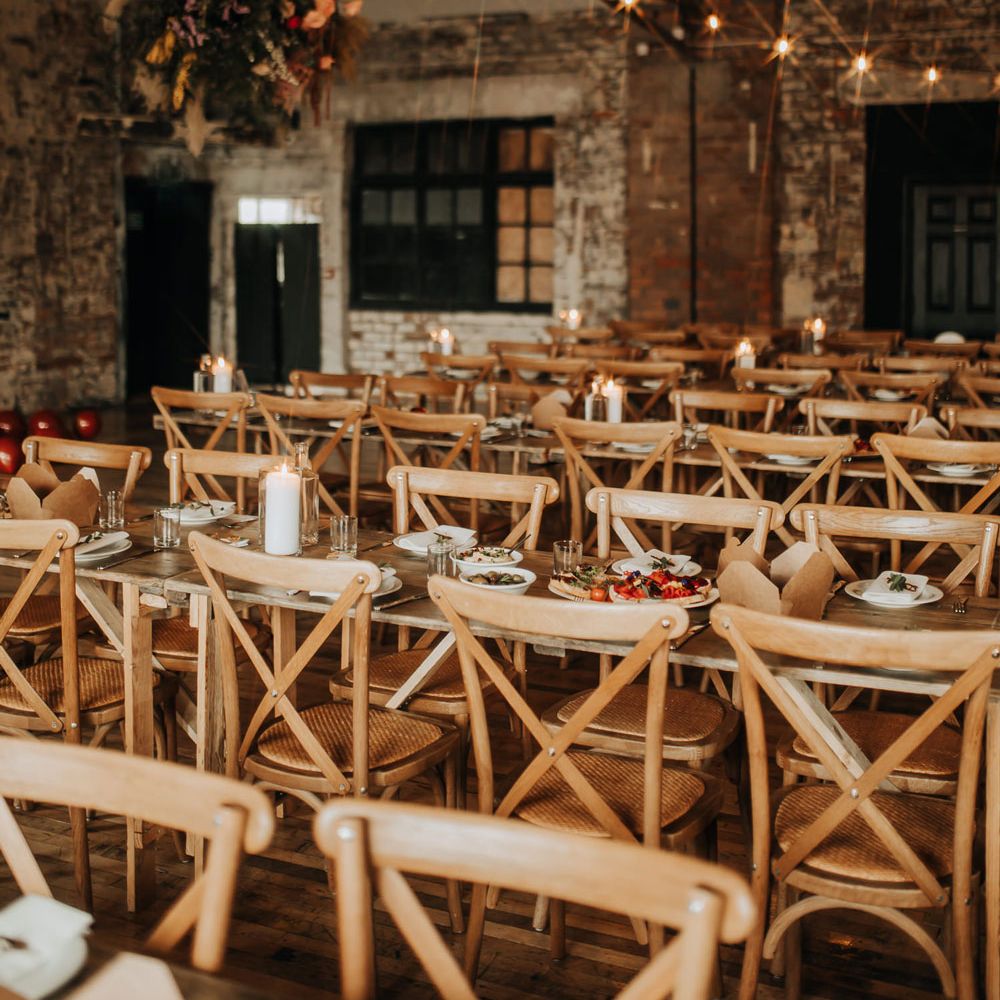 Long wooden tables with wooden chairs in reception room at industrial wedding venue in Liverpool