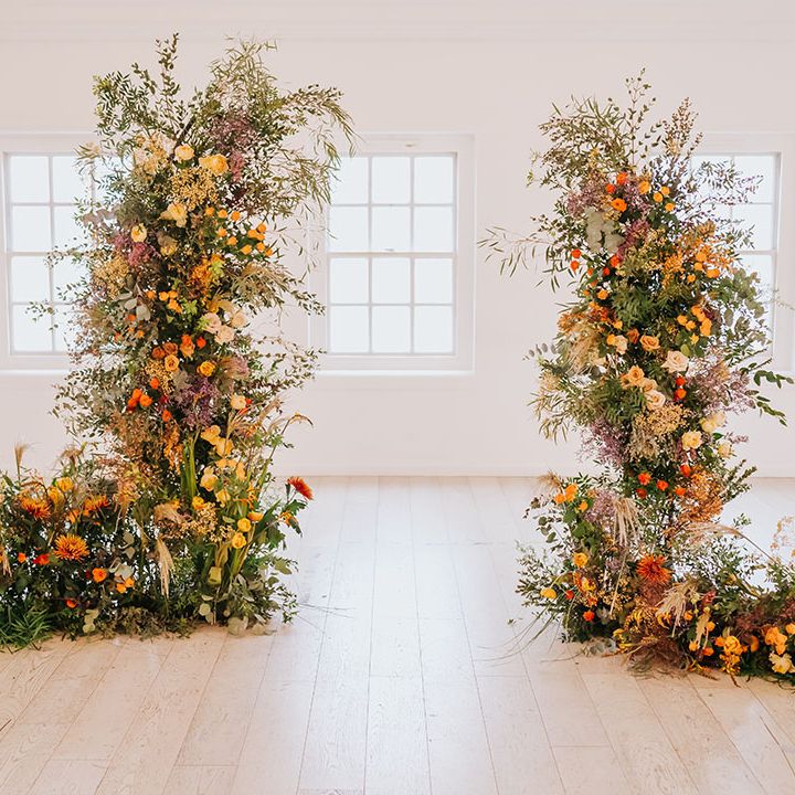 Orange, yellow and green foliage column wedding flower arrangement at minimalist wedding venue 