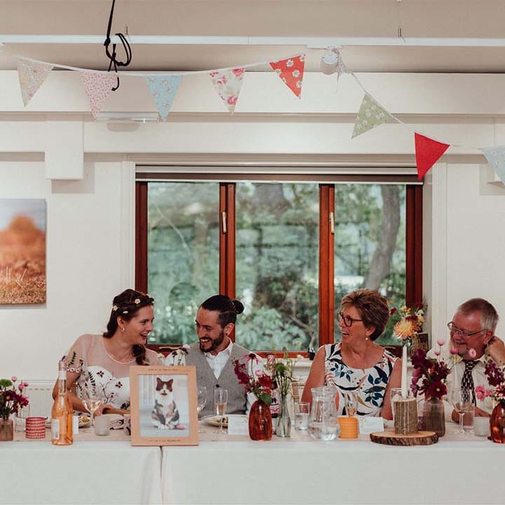 Top table with picture of their pet cat in wooden frame with tree trunk candle holders and floral bunting
