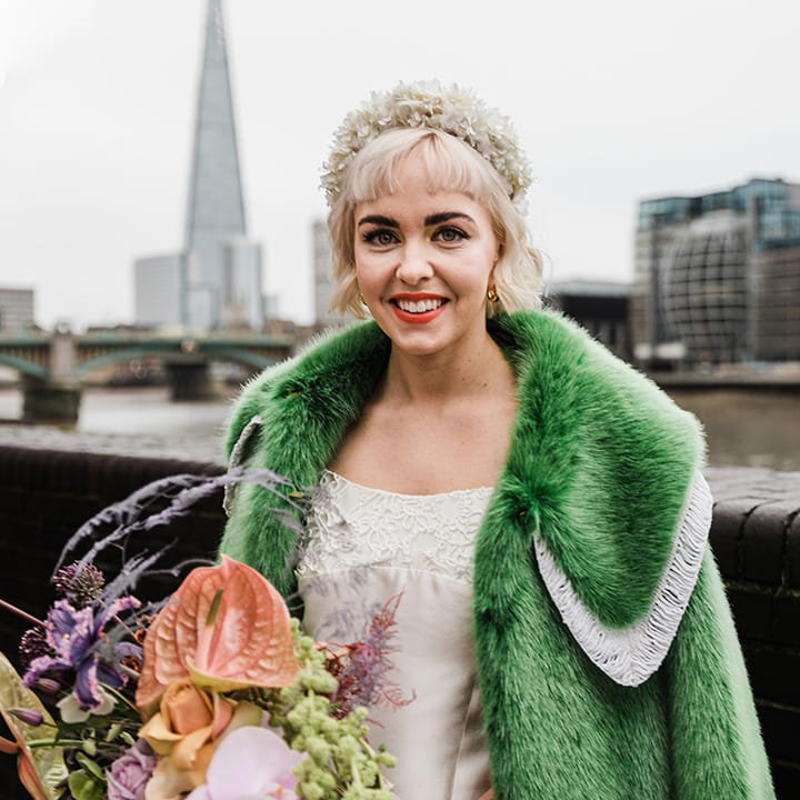 Bride with short blonde hair and white flower headband with green fur coat and white wedding dress