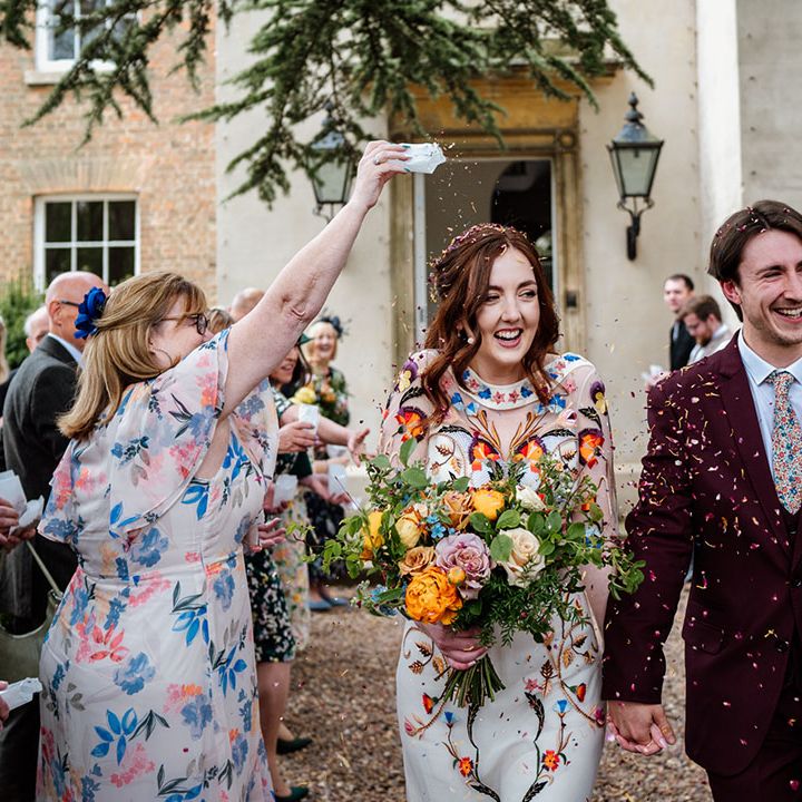 Bride and groom exit their ceremony to colourful confetti thrown by the wedding guests to celebrate 
