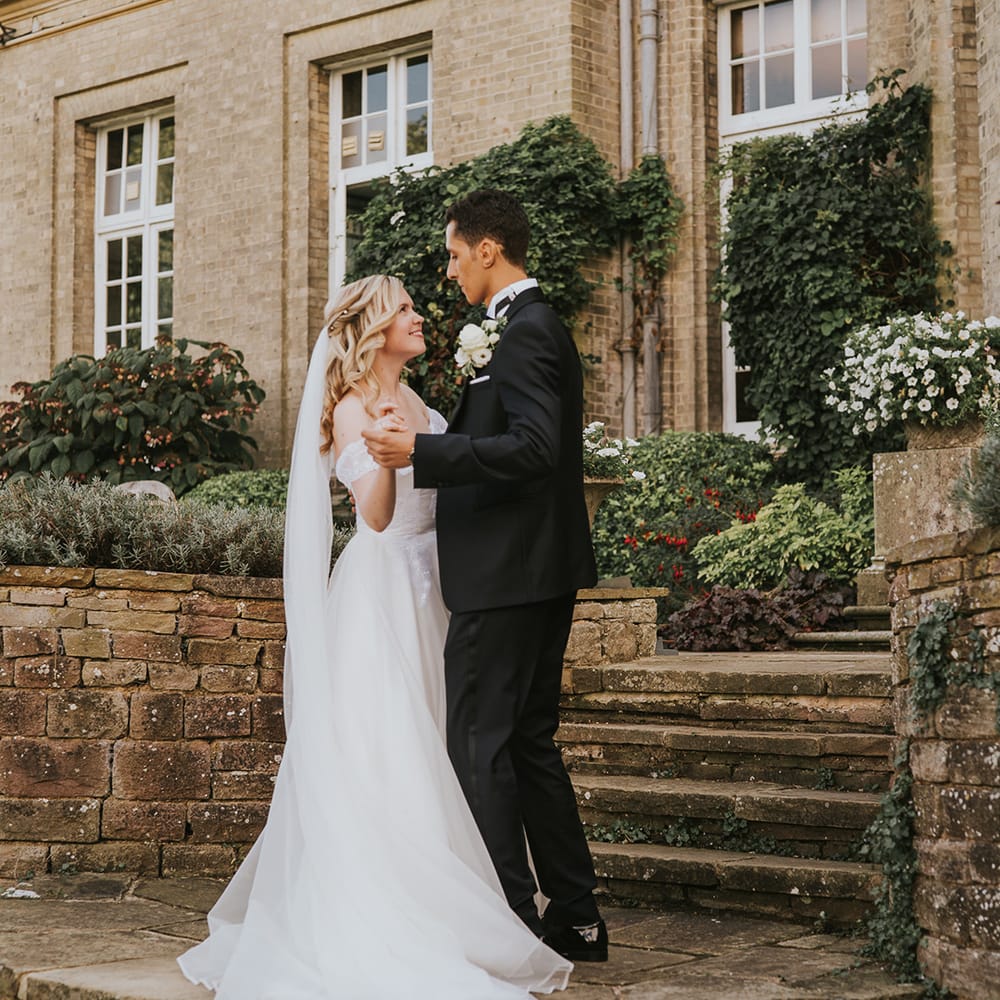 Bride and groom hold hands together for their country house wedding 