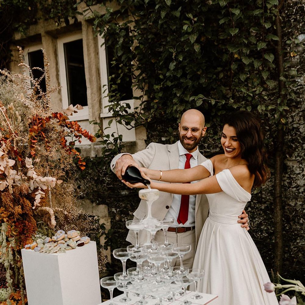 Outdoor dessert station with the bride and groom pouring champagne over their champagne tower 