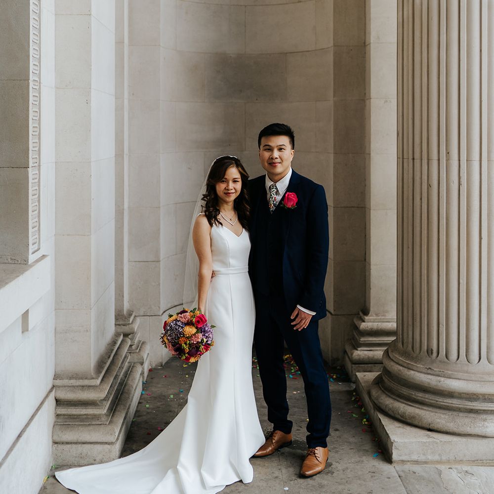 Groom in three piece suit stands beside his bride at the Old Marylebone Town Hall