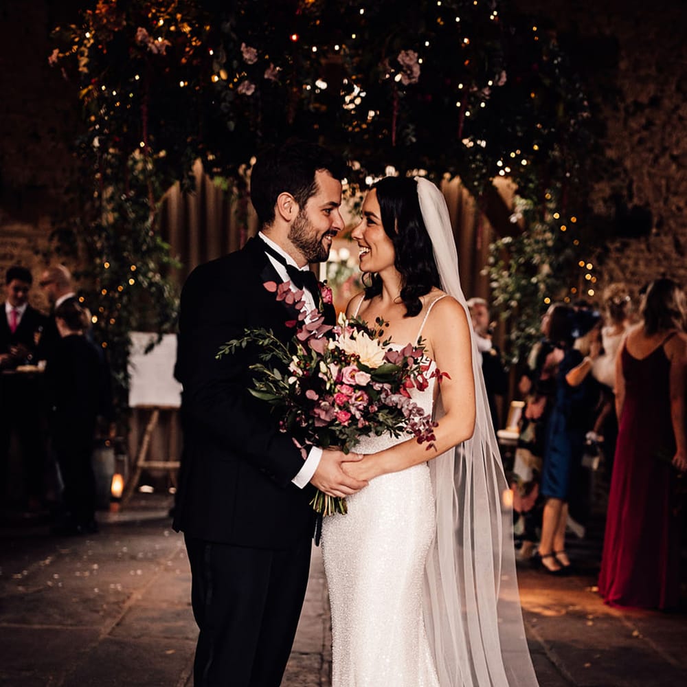 Bride in a beaded sparkle wedding dress from Made With Love gazes into the groom's eyes 