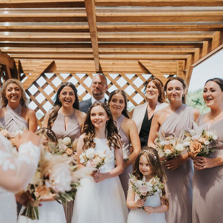 Bridesmaids in pink bridesmaid dresses with mismatched styling see bride for the first time 