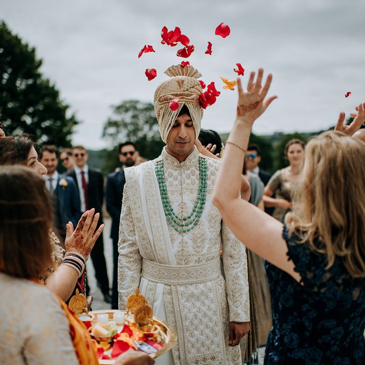 Colourful petals are thrown toward groom during Haldi ceremony outdoors 