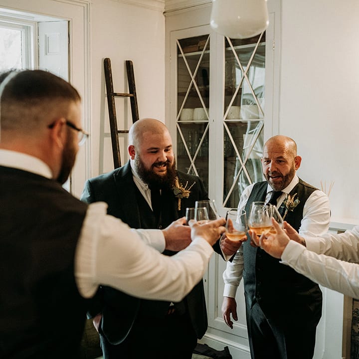 Groom and groomsmen share a shot of whiskey on the morning of the wedding 